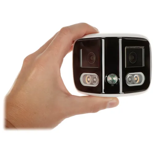 Na zdjęciu widać rękę trzymającą urządzenie z dwoma kamerami i trzema okrągłymi diodami na czarnym panelu. Urządzenie ma kompaktowy, prostokątny kształt z zaokrąglonymi krawędziami.