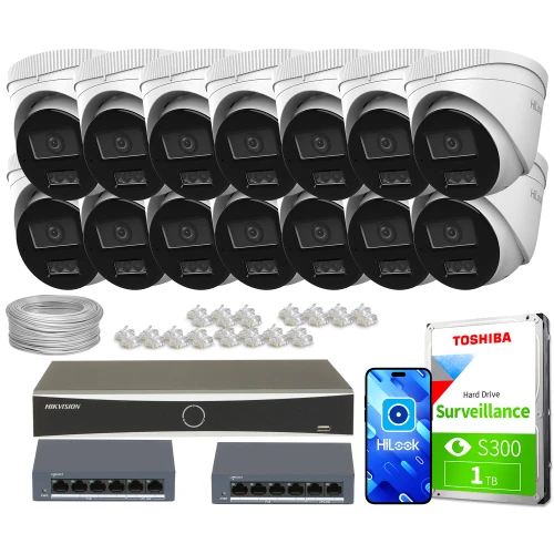 Na zdjęciu znajduje się zestaw do monitoringu, który obejmuje czternaście kamer, dysk twardy Toshiba o pojemności 1TB, dwa przełączniki sieciowe oraz rejestrator Hikvision. W tle widoczne są również kable i złącza potrzebne do instalacji systemu.