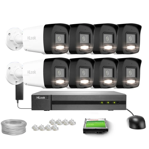 Na zdjęciu znajduje się zestaw do monitoringu, składający się z ośmiu kamer, rejestratora, dysku twardego, kabla oraz złączy. Kamery są ułożone w dwóch rzędach nad rejestratorem, a obok nich widoczna jest mysz komputerowa.