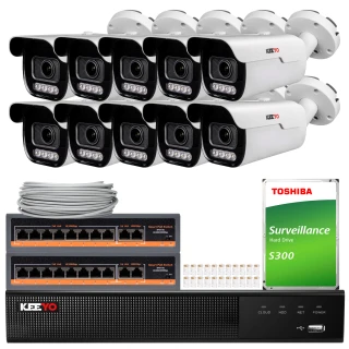 Na zdjęciu znajduje się zestaw do monitoringu, który obejmuje osiem kamer, dwa przełączniki sieciowe, dysk twardy Toshiba oraz rejestrator wideo. Kamery są białe z czarnymi elementami, a pozostałe urządzenia mają czarne i pomarańczowe akcenty.